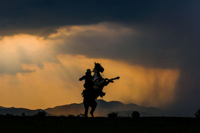 Man riding horse against sky during sunset