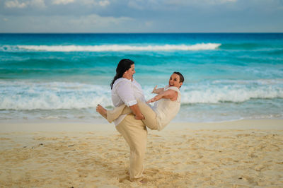 Rear view of couple at beach against sky