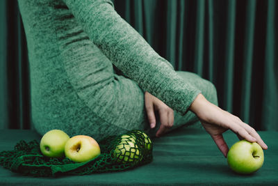 Midsection of woman holding apple on table