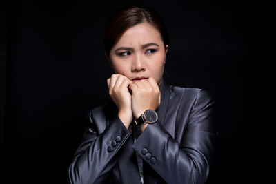 Worried businesswoman looking away against black background