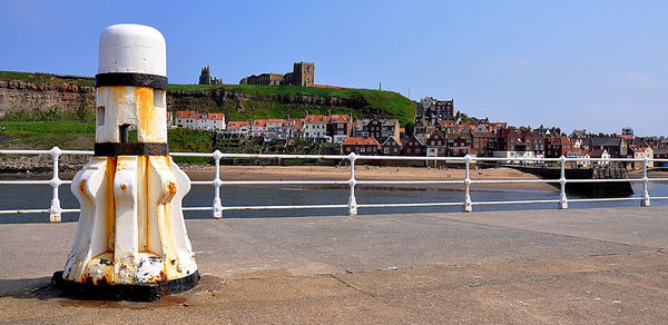 Old building by river against clear blue sky