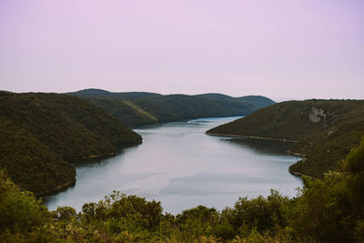 Scenic view of sea and mountains against clear sky