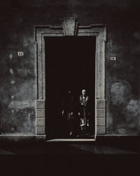 A manequin framed inside a shadowy boutique display, in black and white