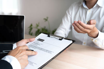 Midsection of man using smart phone on table