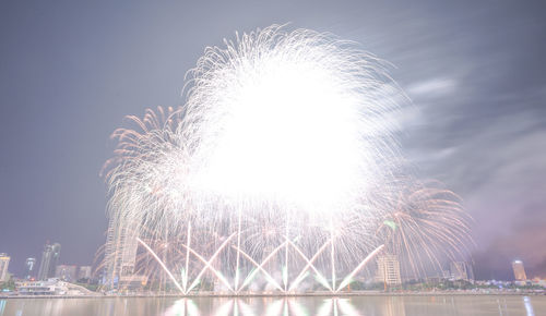 Low angle view of firework display over river against sky