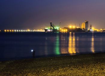 Illuminated pier by sea against sky at night