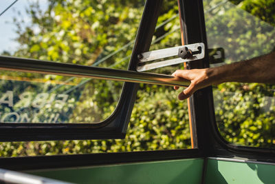 Cropped hand of man by window in bus