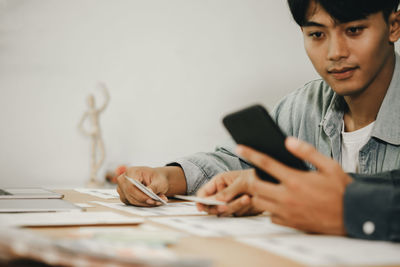 Man using mobile phone while sitting on table