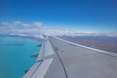 Airplane flying over sea against blue sky