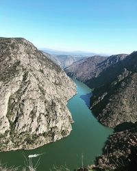 Scenic view of river and mountains against clear blue sky