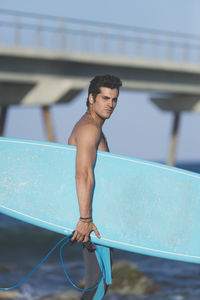 Shirtless man with surfboard at beach