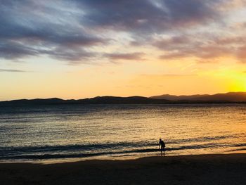 Silhouette man on beach against sky during sunset