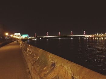 Illuminated bridge over city against sky at night