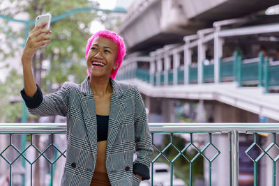 Portrait of smiling young woman using mobile phone outdoors