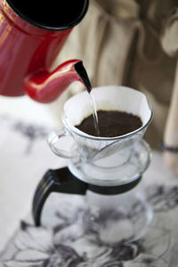 Close-up of jug pouring water in coffee cup at table