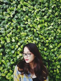 Smiling beautiful woman looking away against plants