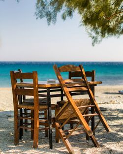 Chairs and table at beach against sky