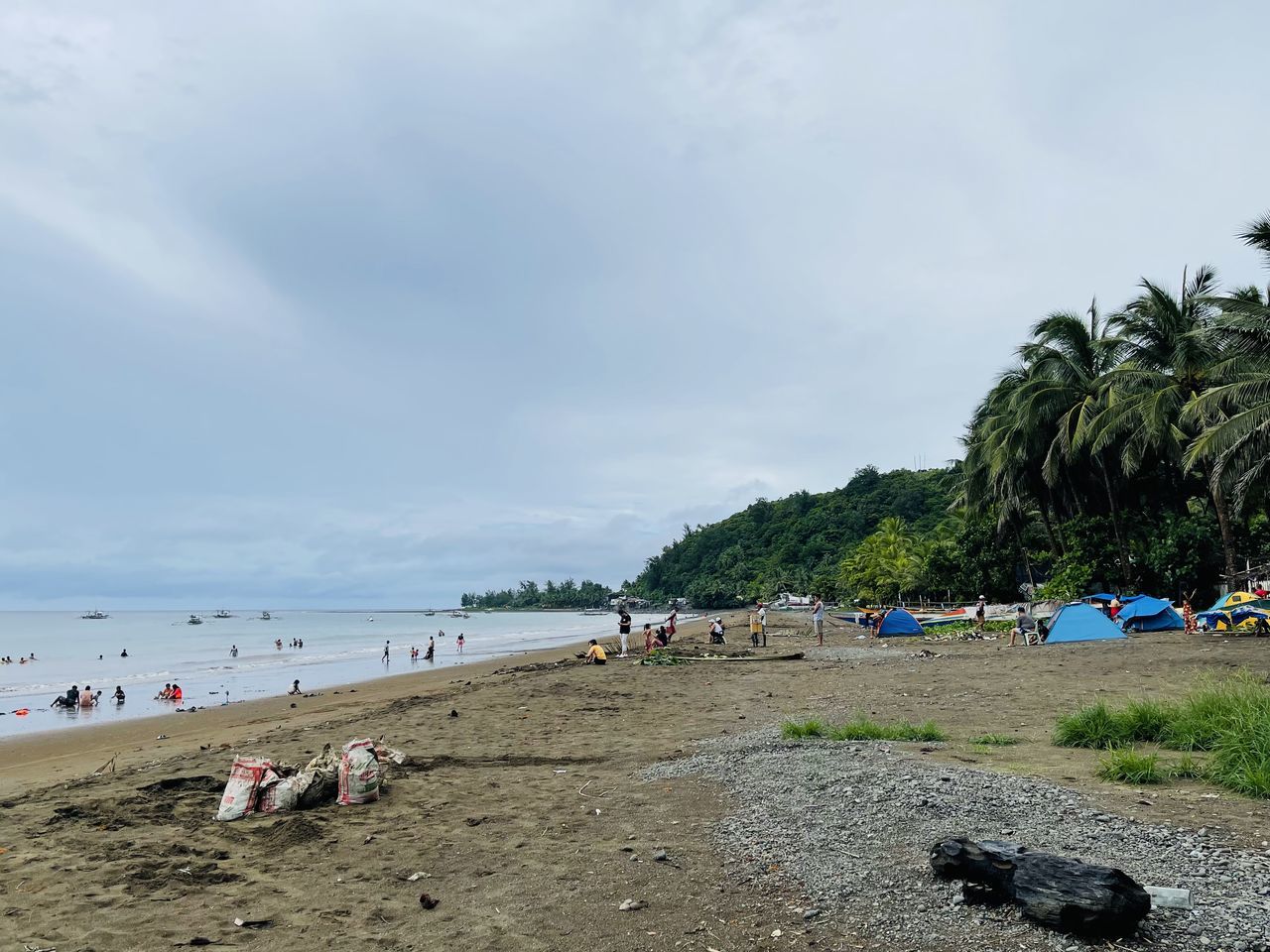 beach, land, sea, water, body of water, sky, sand, nature, holiday, coast, vacation, trip, shore, large group of people, tree, cloud, group of people, ocean, tropical climate, crowd, beauty in nature, scenics - nature, travel destinations, palm tree, travel, plant, relaxation, tourism, day, coastline, leisure activity, outdoors, summer, tourist, bay, tranquility, environment, hut, idyllic, tranquil scene, lifestyles, island, non-urban scene, men