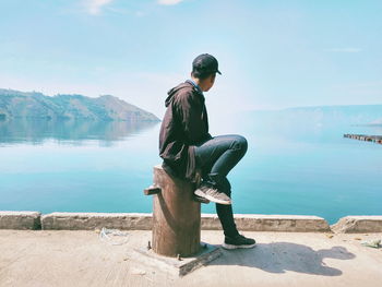 Man sitting on looking at sea against sky