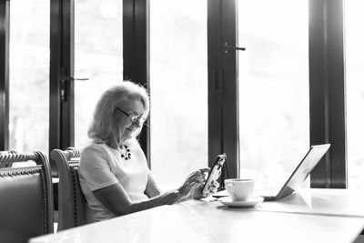 Woman using phone on table at home