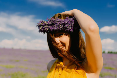 Rear view of woman with arms raised standing against sky