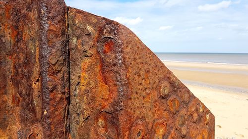 Close-up of rusty metal on beach against sky