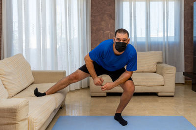 Man wearing flu mask exercising at home