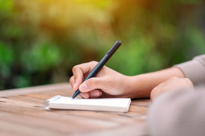 Midsection of woman reading book on table