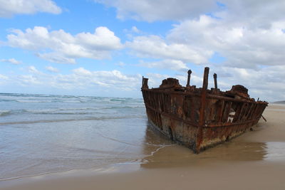 View of obsolete rusty boat on shore of beach