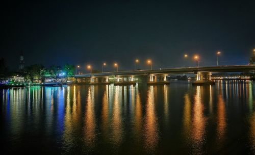 Illuminated bridge over river against sky at night