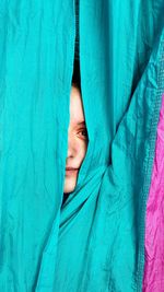 Close-up portrait of woman peeking through textile