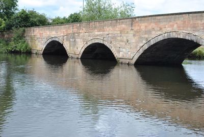 Arch bridge over river against sky