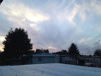 Houses against cloudy sky at sunset