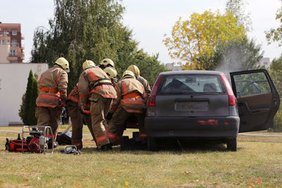 Fire fighters working while standing by car