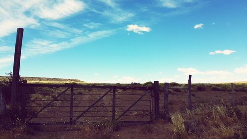 Fence on field against cloudy sky