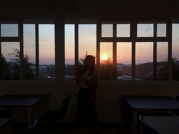 Rear view of silhouette woman standing against window
