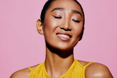 Portrait of young woman against pink background