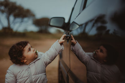 Girl opening car door while standing on land