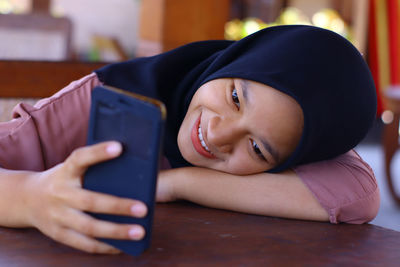 Portrait of smiling girl using mobile phone at home