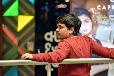 Young man looking away while sitting on railing