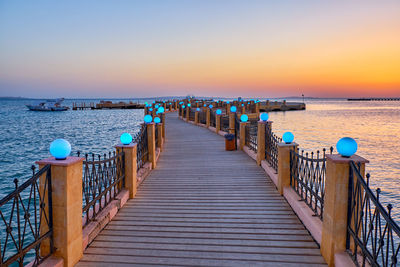 Pier over sea against sky during sunset