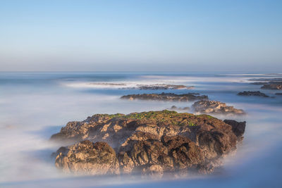 High angle view of rocks at coastline surrounded by fog