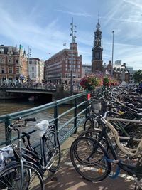 Bicycle parked by bridge over river against buildings in city