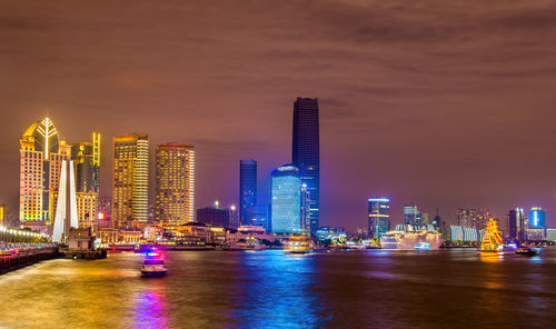 Illuminated buildings in city against sky at night