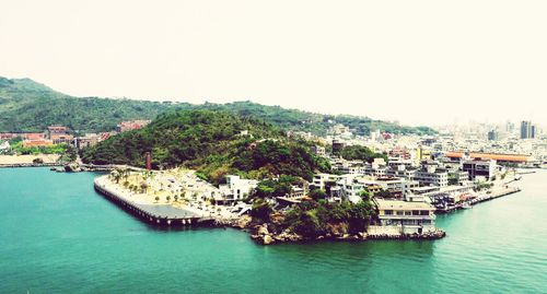 Aerial view of townscape by sea against clear sky