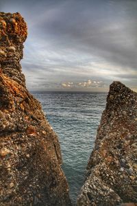 Rocks by sea against sky during sunset