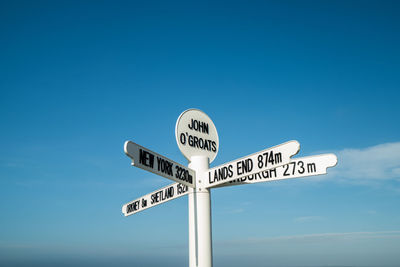 Low angle view of road sign against blue sky