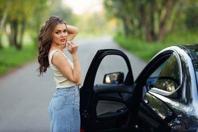 Portrait of smiling young woman standing in car