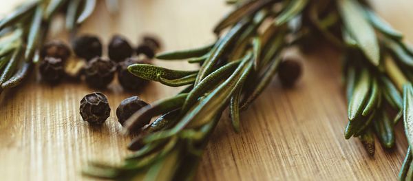 High angle view of black peppercorns and rosemary on table