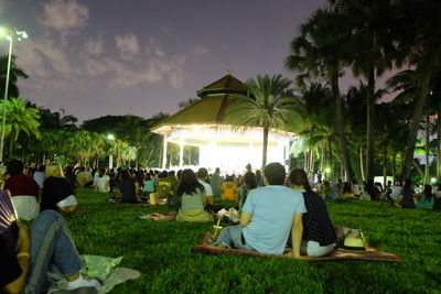 People enjoying musical concert at park during dusk